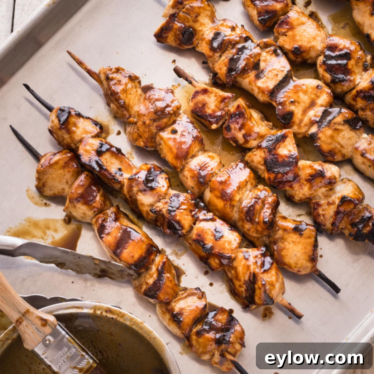 Grilled chicken kabobs glazed with hoisin sauce on a baking sheet.