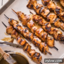 Grilled chicken kabobs glazed with hoisin sauce on a baking sheet.