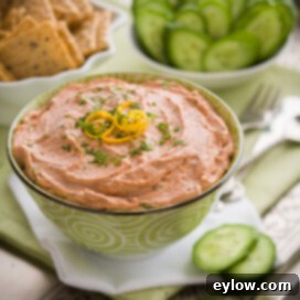 Creamy salmon dip on an appetizer tray with crackers and cucumber chips.