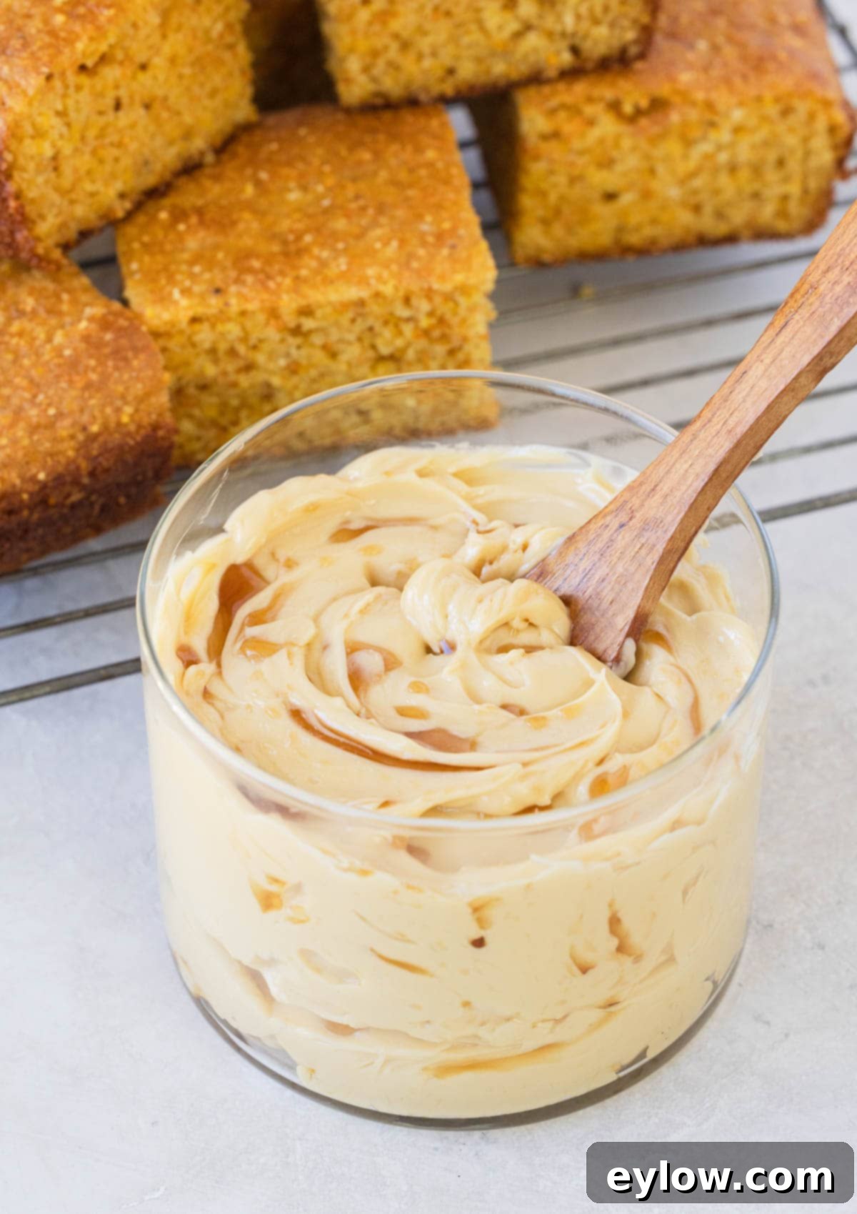 A glass jar filled with yellow, whipped maple butter, with a drizzle of maple syrup on top, ready to be served.
