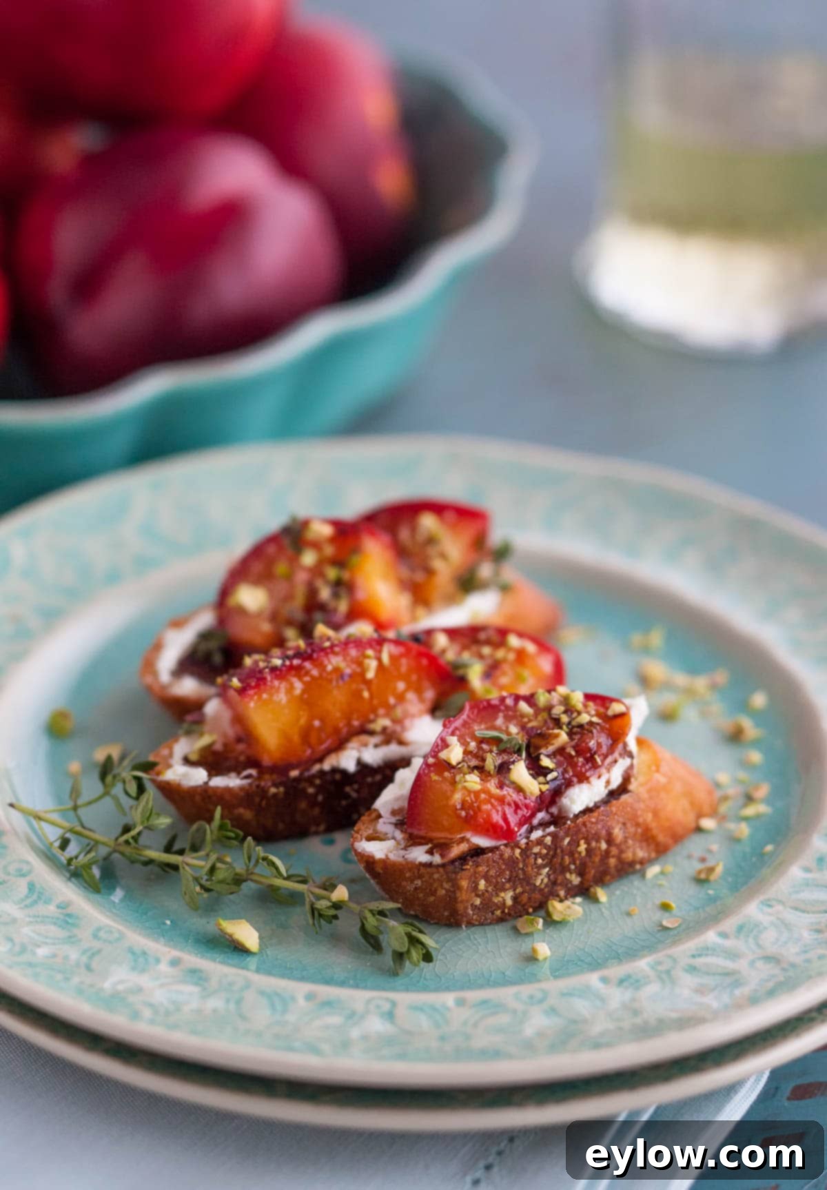 Blushing Nectarine Goat Cheese Crostini 2 Roasted nectarines on crostini with goat cheese on a blue plate.