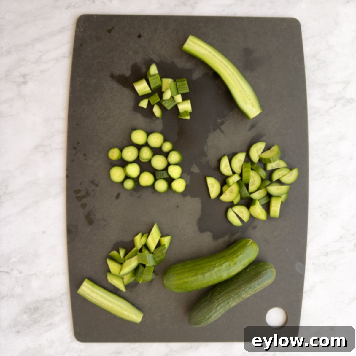Sweet & Savory Watermelon Basil Feta Salad 6 Various cuts of fresh cucumber, including slices and diced pieces, arranged on a black cutting board.