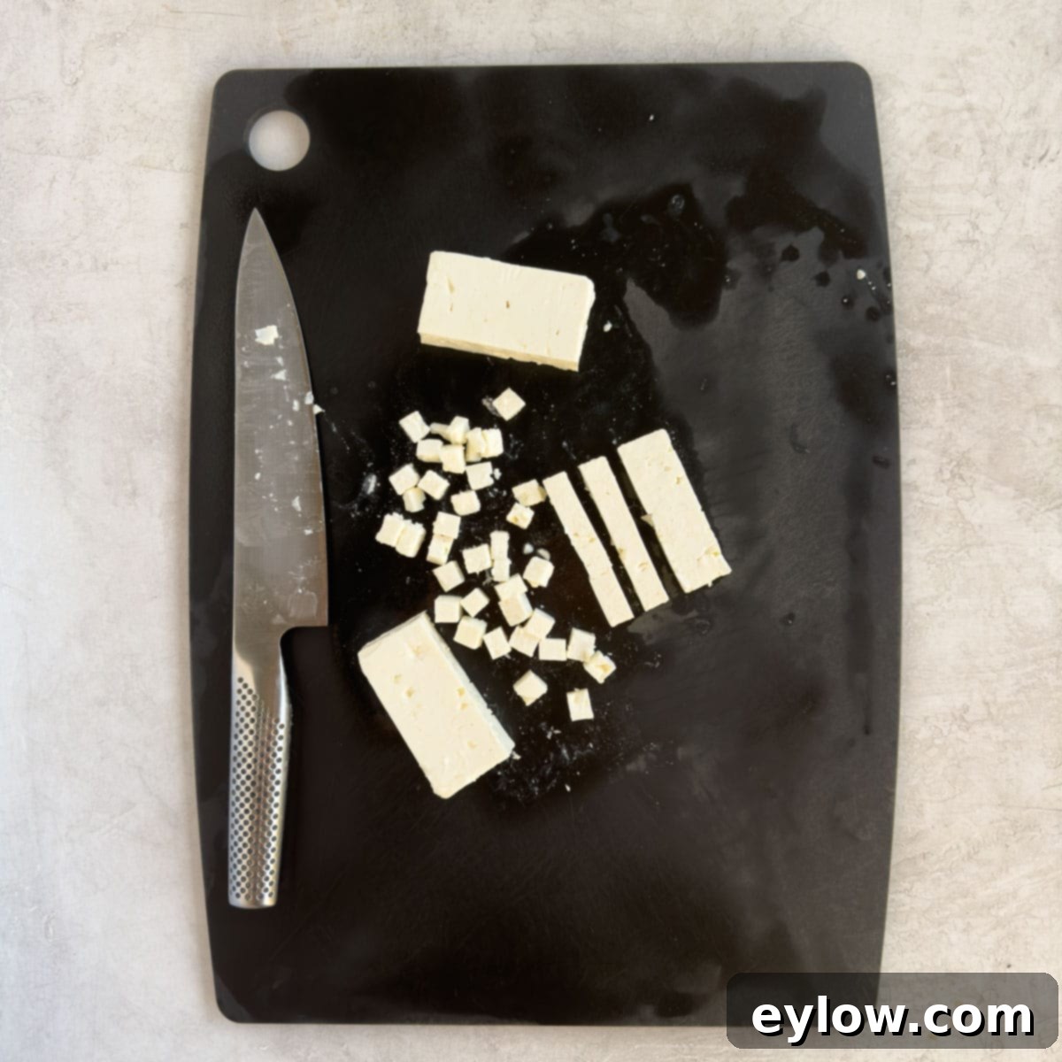 Sweet & Savory Watermelon Basil Feta Salad 7 Hands carefully cutting a block of creamy feta cheese into small, even cubes for a salad.