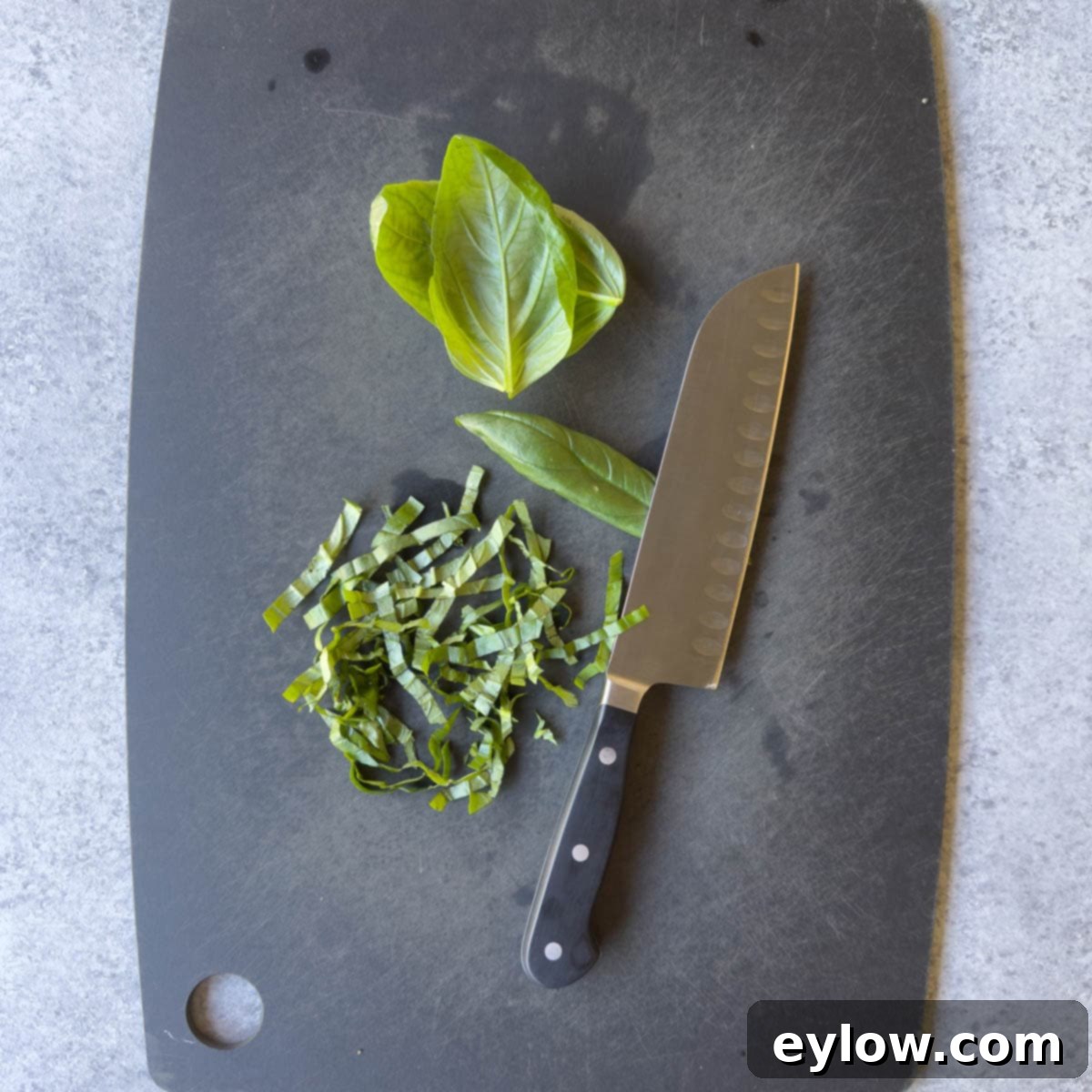 Sweet & Savory Watermelon Basil Feta Salad 8 Bright green fresh basil leaves, rolled into a cylinder and ready for slicing, on a dark cutting board.