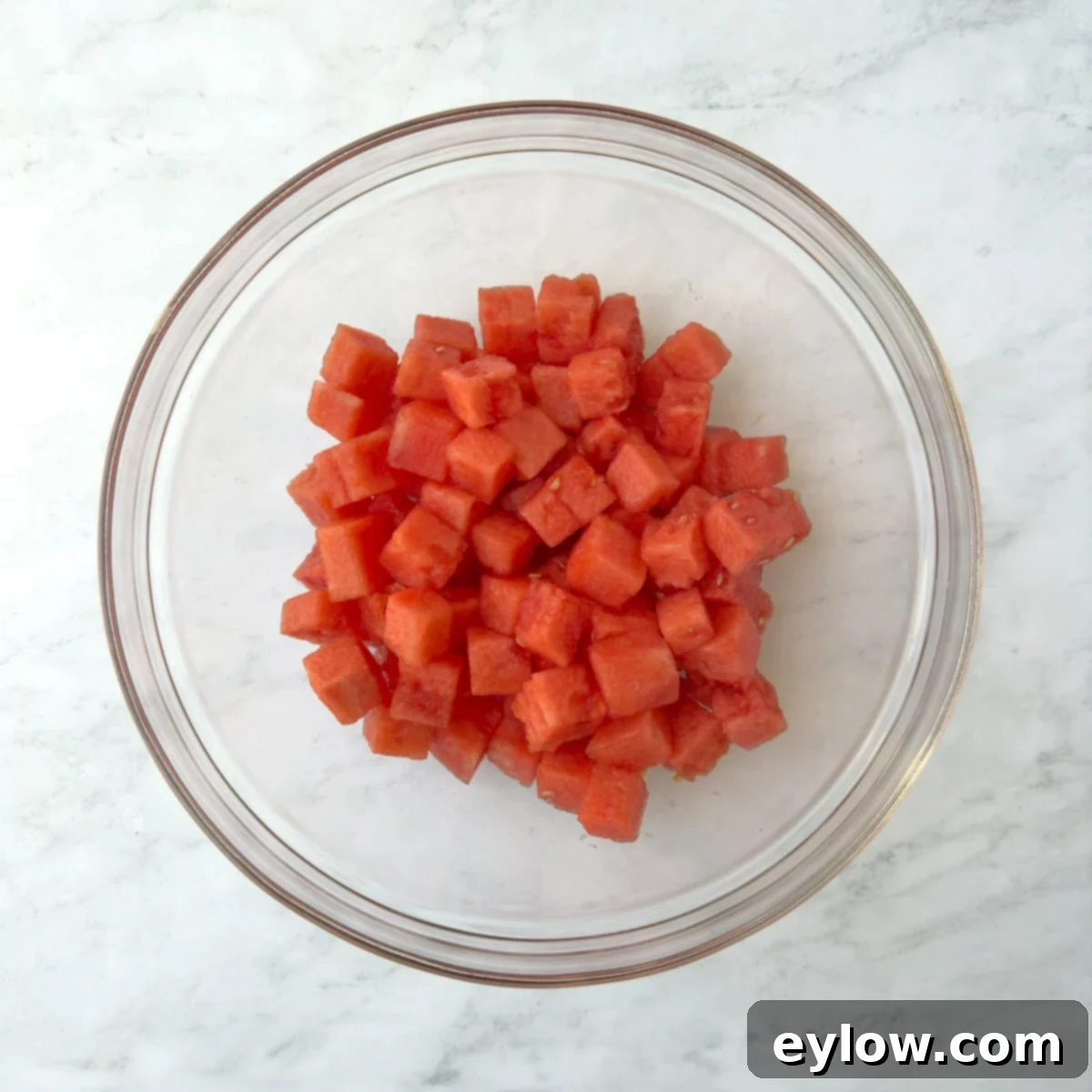 Sweet & Savory Watermelon Basil Feta Salad 9 A glass bowl filled with vibrant red, perfectly cubed watermelon pieces, ready for salad assembly.