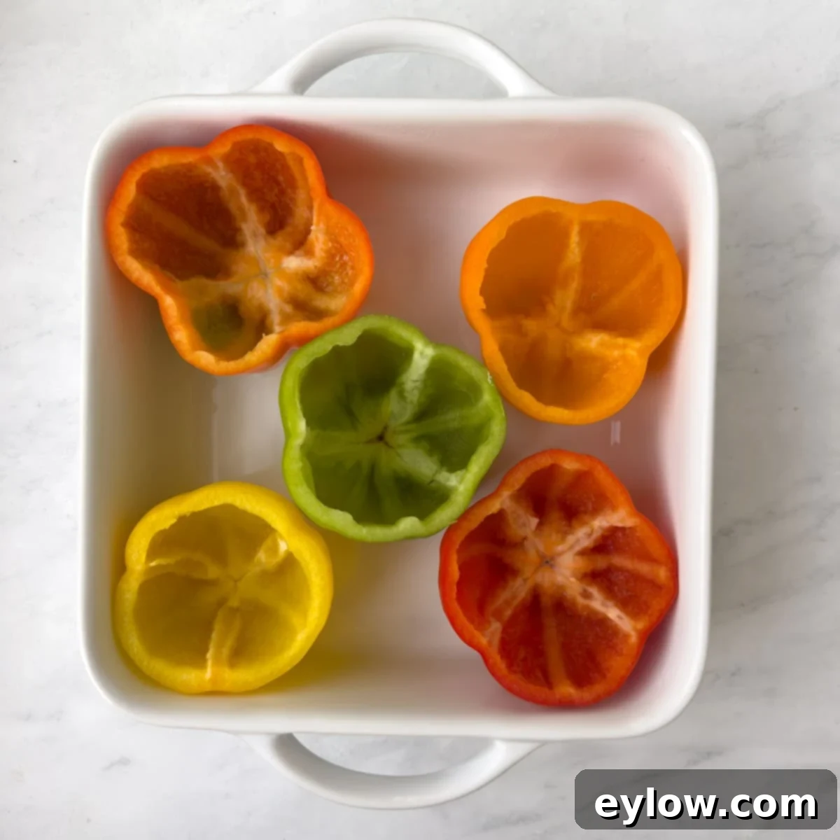 Flavorful Turkey Stuffed Pepper Boats 4 Bell peppers with their tops sliced off, seeds and ribs removed, ready to be filled, arranged in a white baking dish.