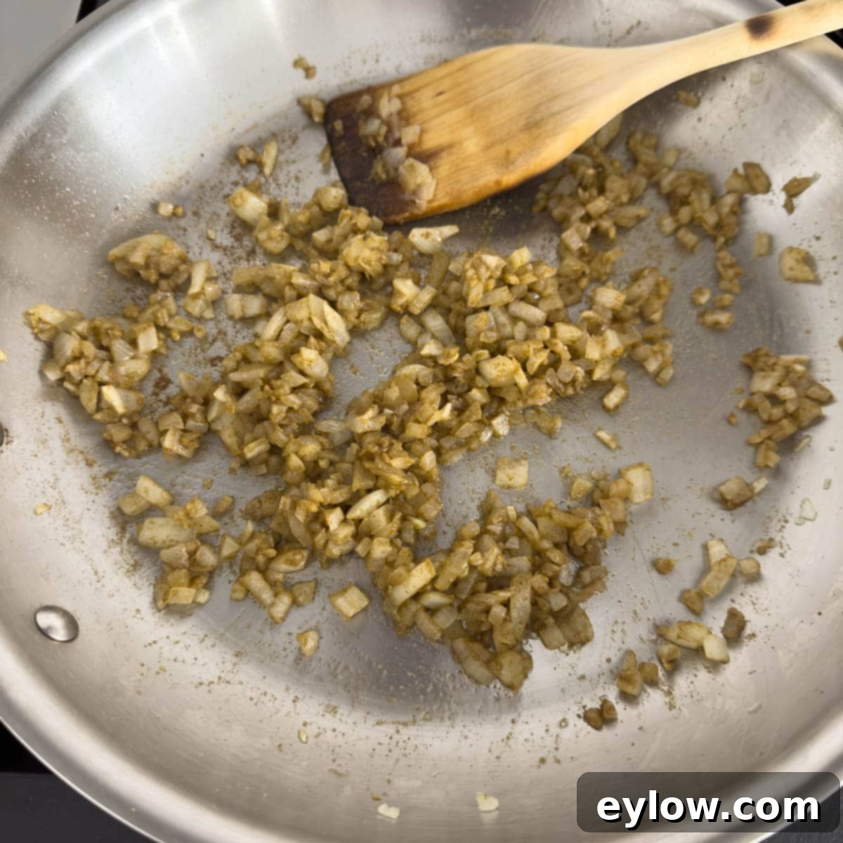 Flavorful Turkey Stuffed Pepper Boats 5 Chopped onions and minced garlic being sautéed in olive oil in a large skillet on the stovetop.