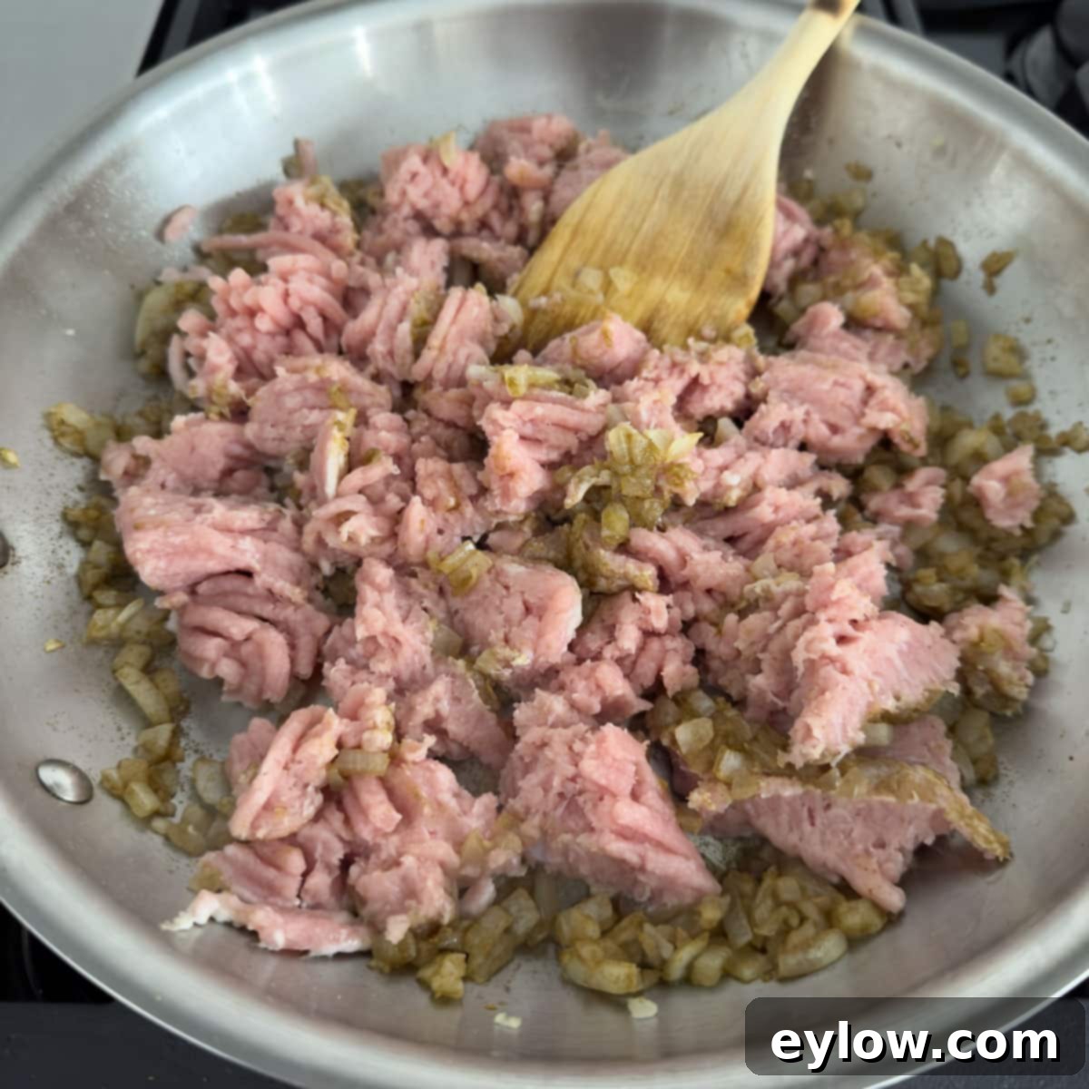 Flavorful Turkey Stuffed Pepper Boats 6 Ground turkey being added to the cooked onions and garlic in a saute pan on the stovetop, ready to be browned.
