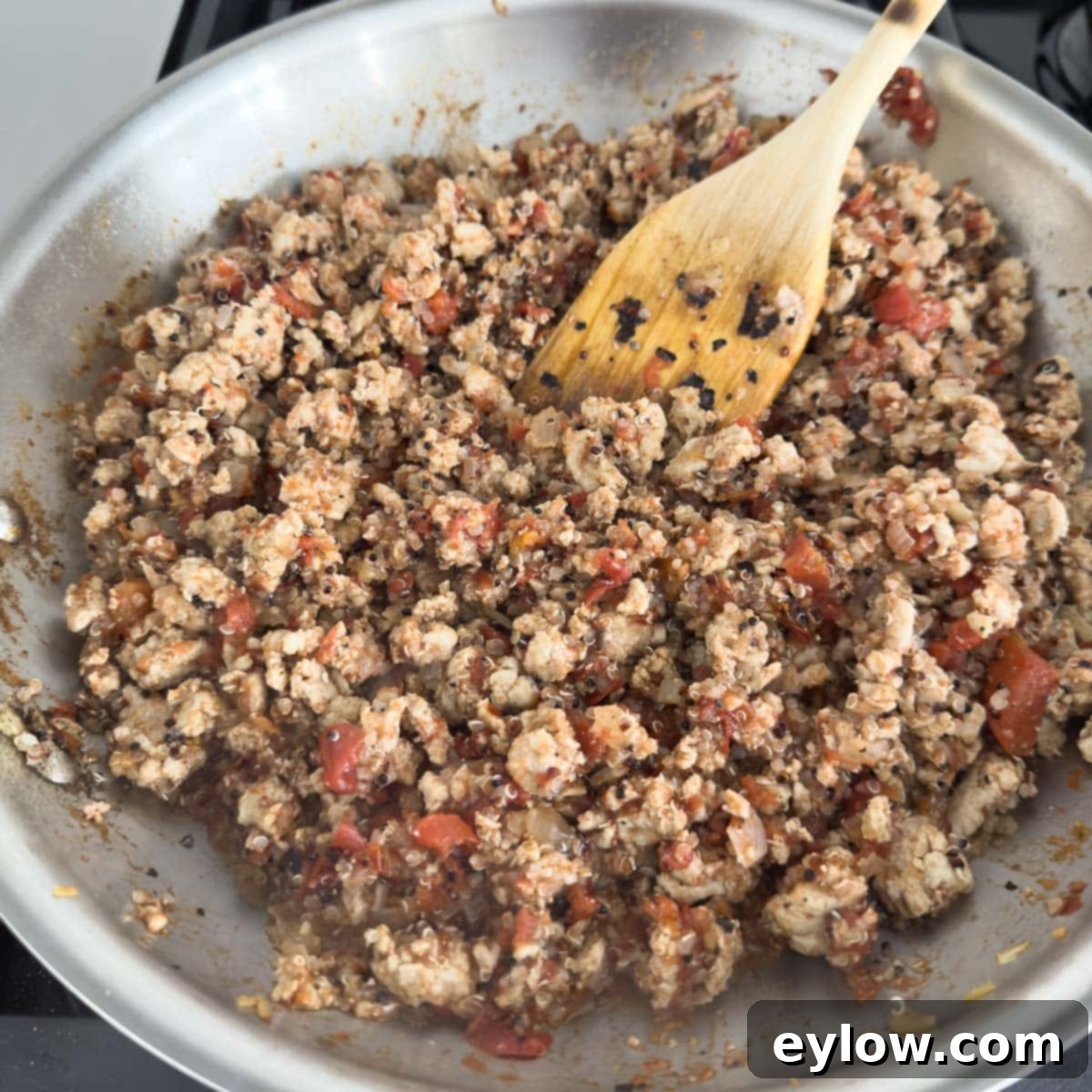 Flavorful Turkey Stuffed Pepper Boats 7 The cooked ground turkey mixture combined with quinoa, diced tomatoes, and spices in a skillet, blending the flavors.