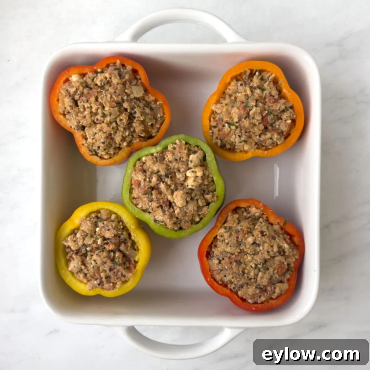 Flavorful Turkey Stuffed Pepper Boats 8 Raw stuffed peppers, generously filled with the ground turkey and quinoa mixture, arranged in a white casserole dish, ready for baking.