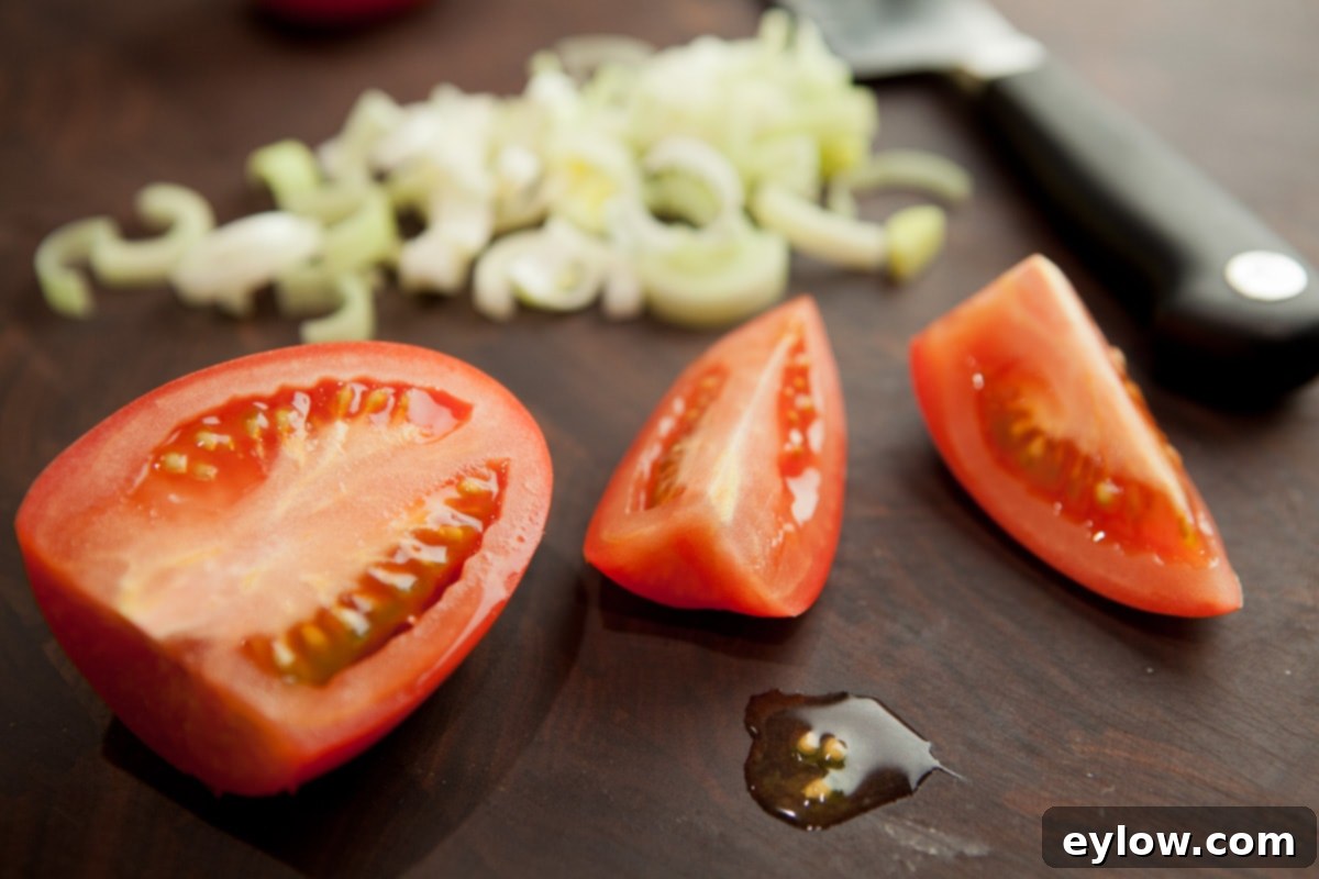 The initial cuts for dicing a tomato, showing the stem end thinly sliced off, followed by the tomato halved, and then quartered.