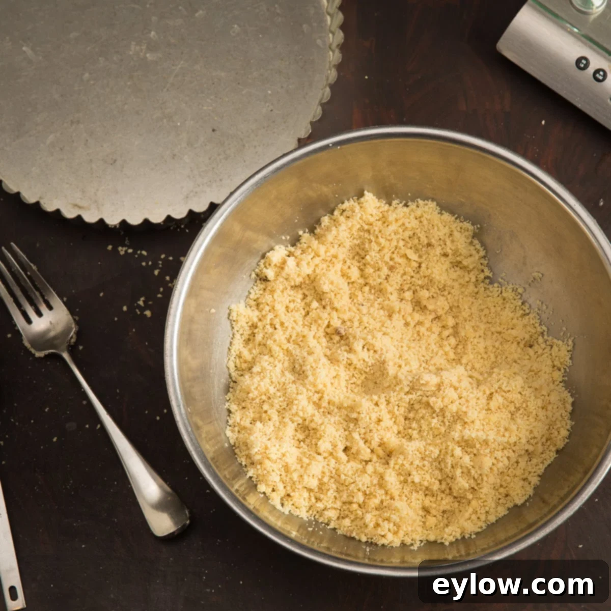 Almond flour, coconut flour, sugar, and salt are blended together in a mixing bowl with a fork, preparing for the butter.