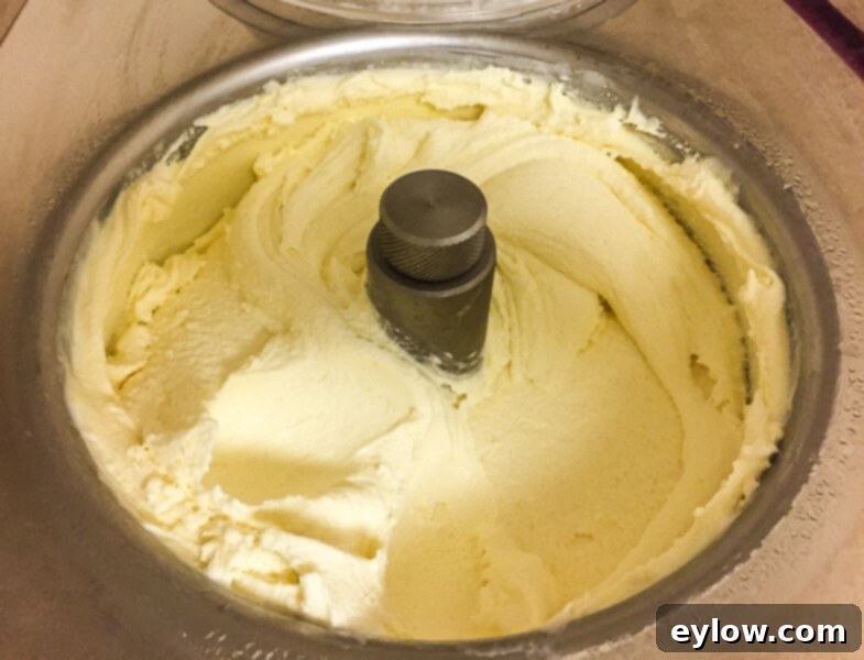 The finished lemon custard ice cream being churned in a silver ice cream maker, ready to be scooped and enjoyed.