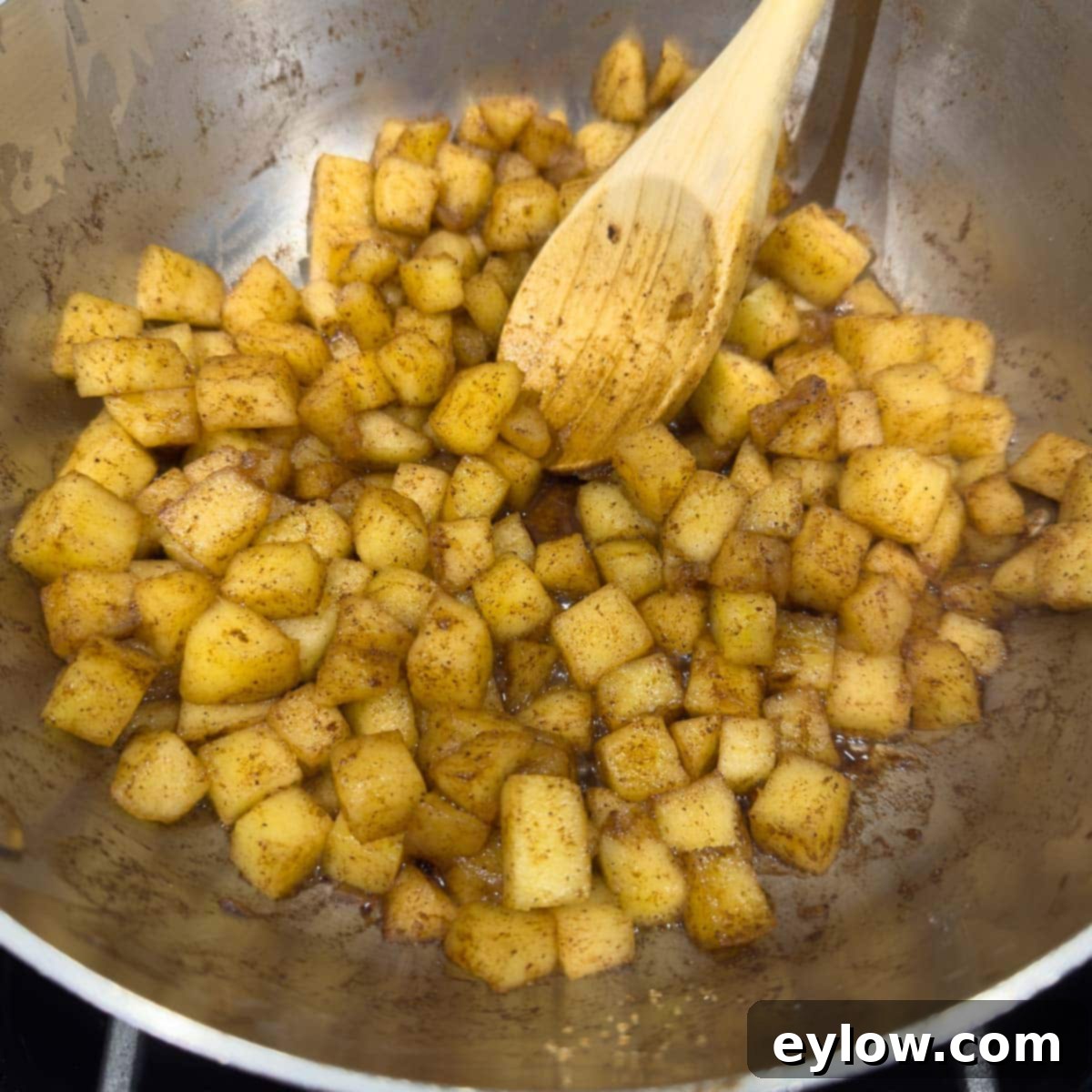 Cooked apples and spices for apple compote in a pan.