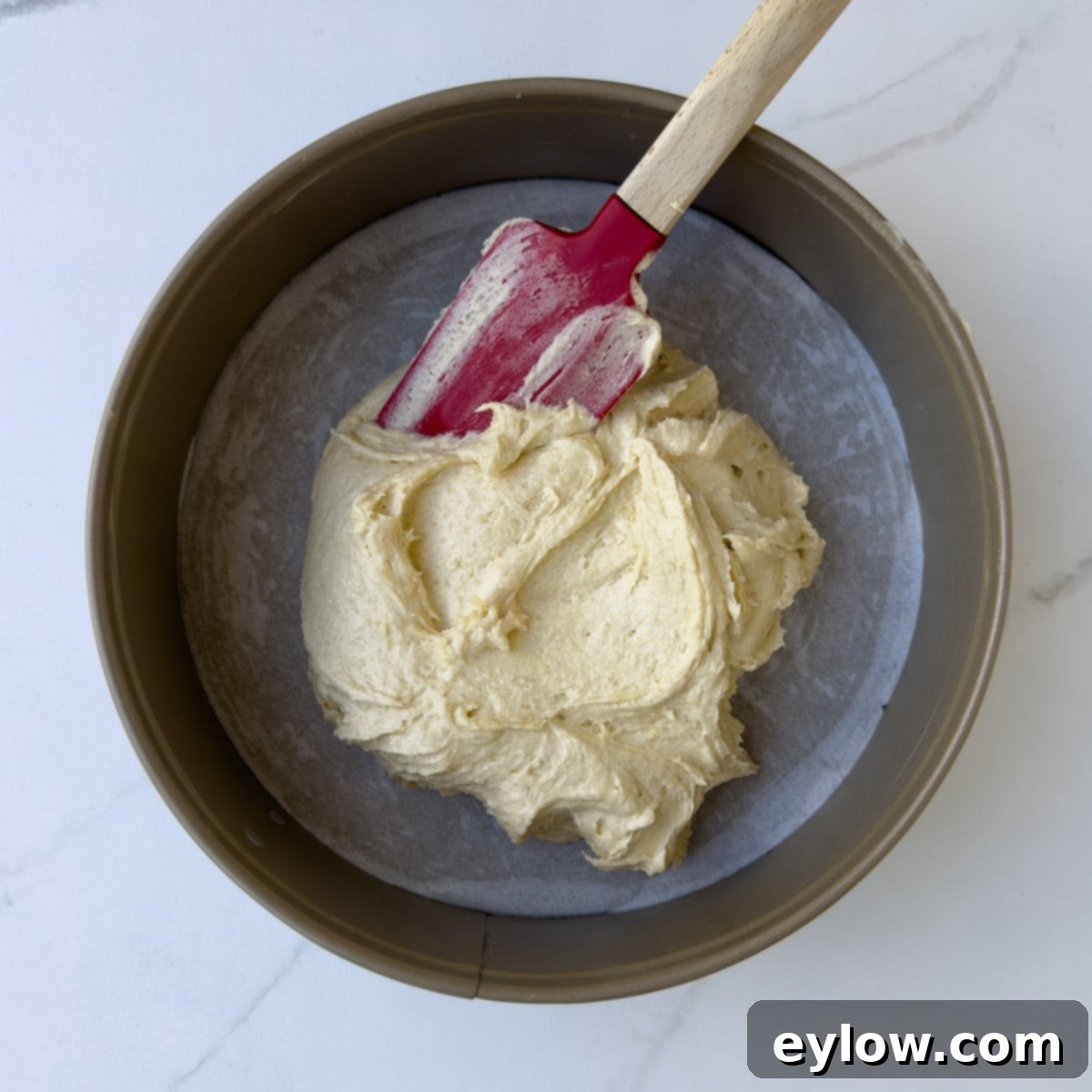 Thick cake batter in a cake pan to be spread out with a spatula.
