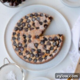 A single layer sweet cherry cake with golden top on white plate.