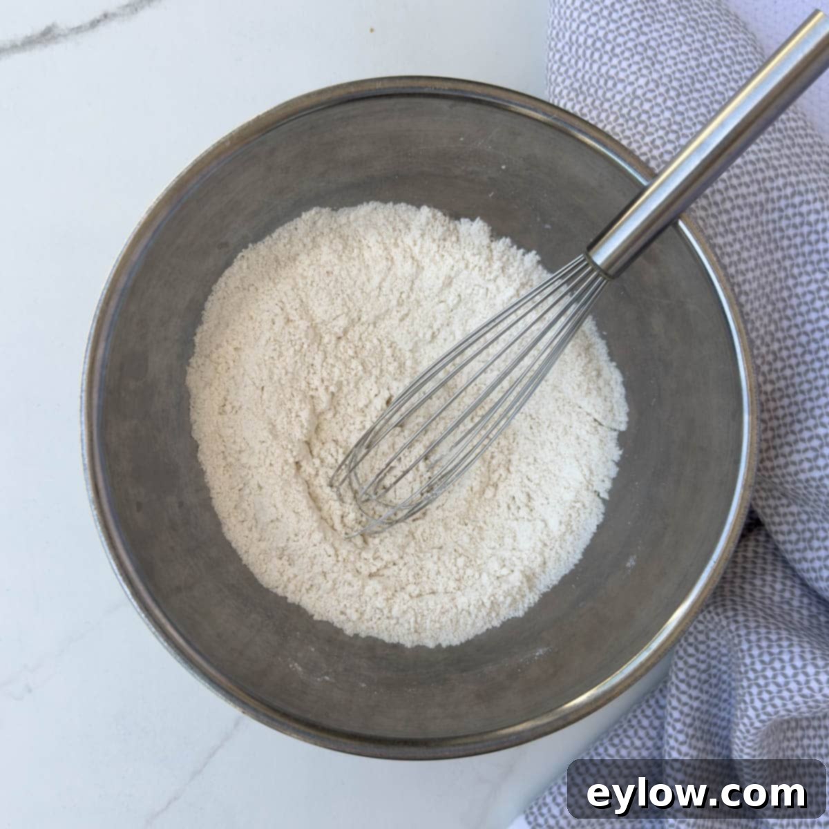 Adding dry ingredients to a bowl and whisk together.