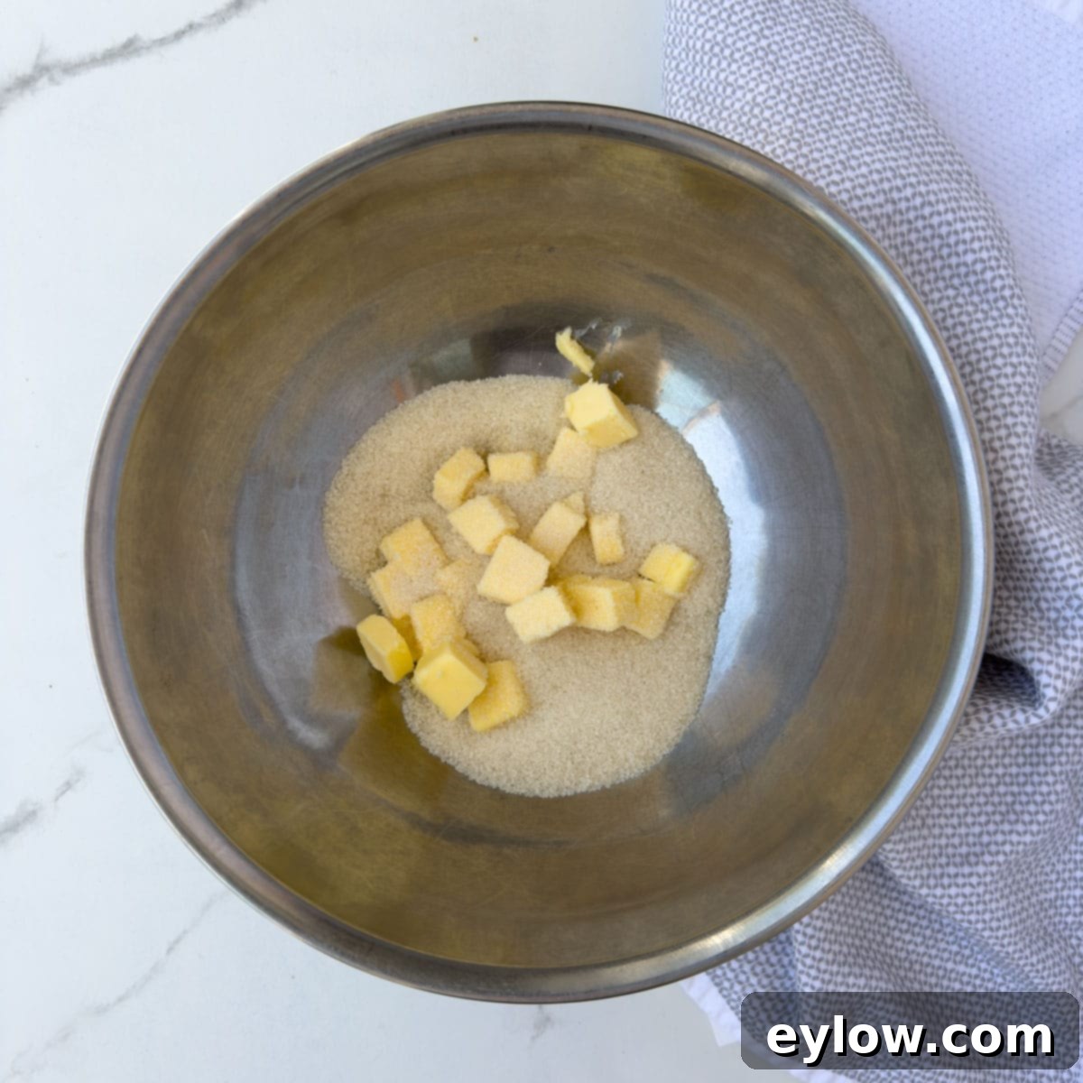 Adding soft butter and sugar to a bowl for cake batter. 