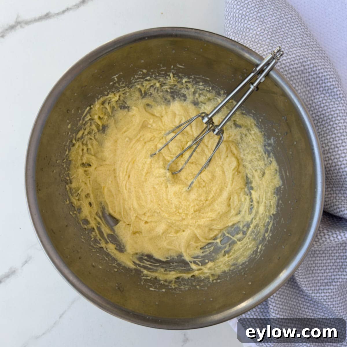Butter yellow batter in a stainless bowl with beaters. 