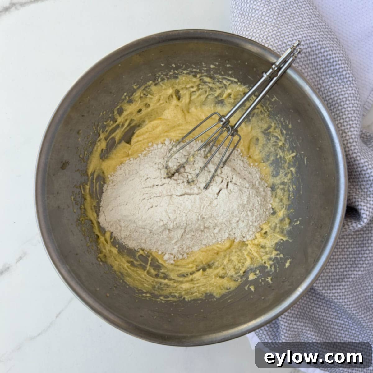 Adding dry ingredients to the batter base for cake batter. 