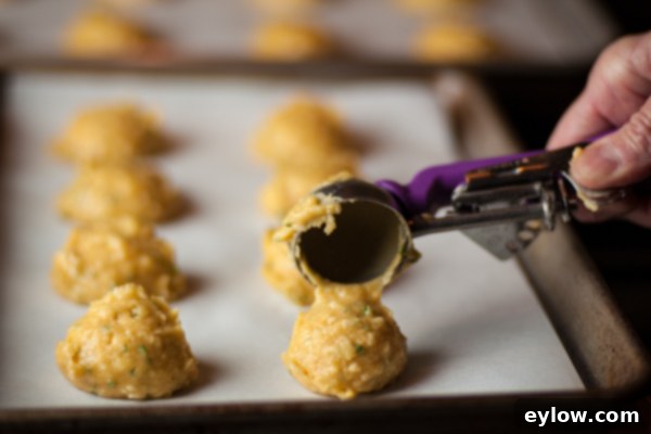 Gougere Cheese Puff-2280 Using a disher tool or cookie scoop to portion dough on to a parchment lined baking sheet for baking.