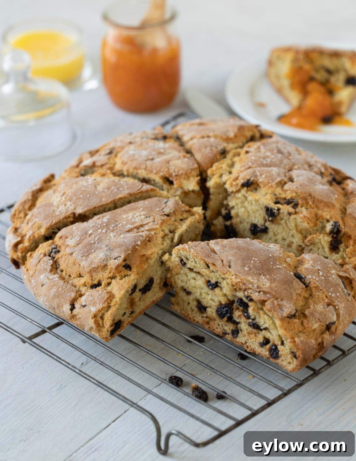 A sliced loaf of Irish soda bread with currants on a cooling rack. 
