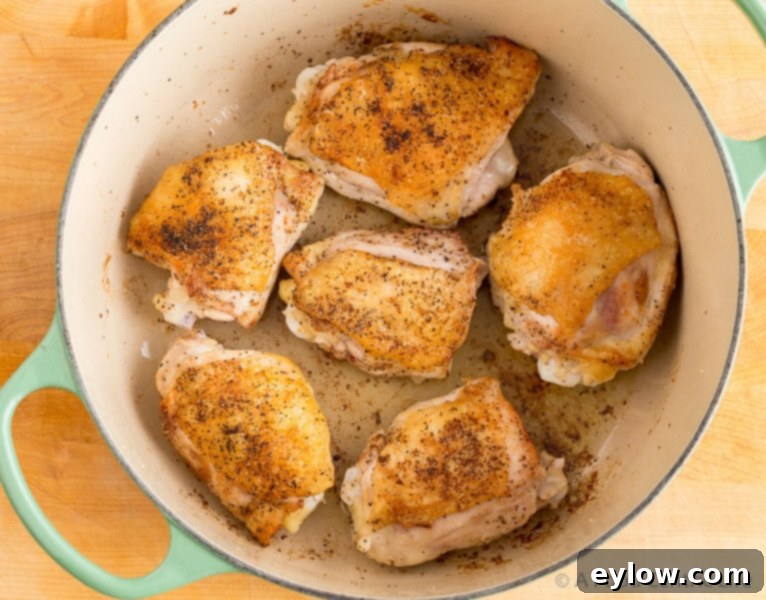 Chicken thighs browning in olive oil in a Dutch oven