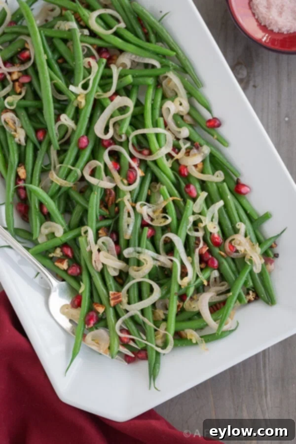 Thanksgiving Green Beans | AFoodCentricLife.com Thanksgiving Green Beans on a white platter with serving fork.