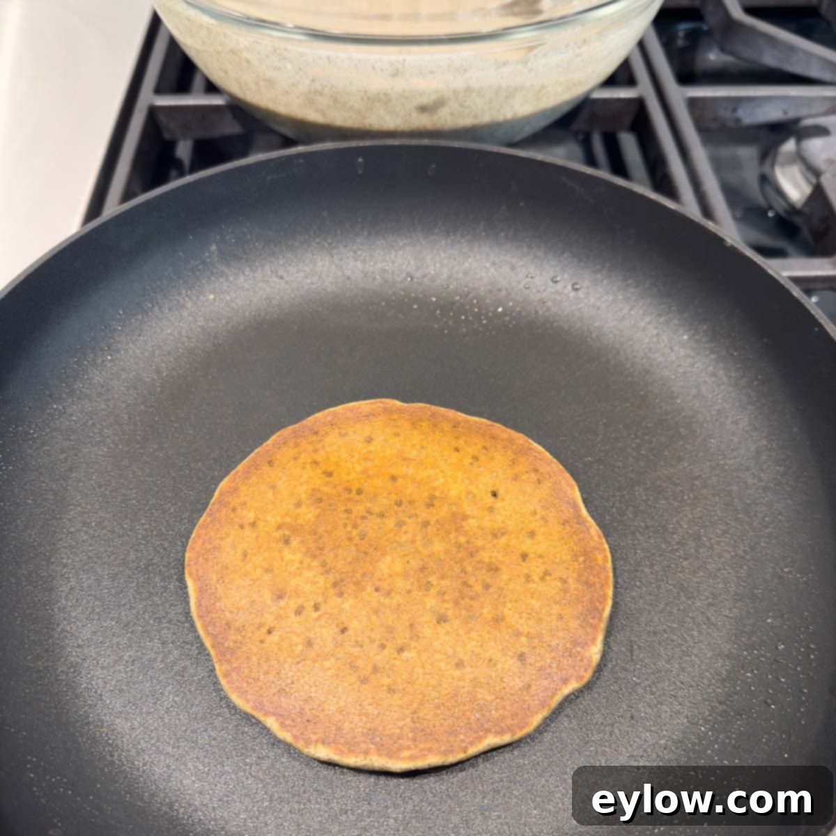A perfectly golden-brown buckwheat pancake, freshly cooked, resting in the pan, indicating it's ready for serving.