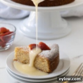 A golden slice of lemon olive oil cake, made wit whole almonds, served with berries and glaze.