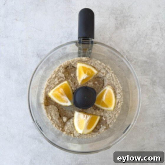 Grinding whole almonds, sugar, and lemon in a food processor bowl.