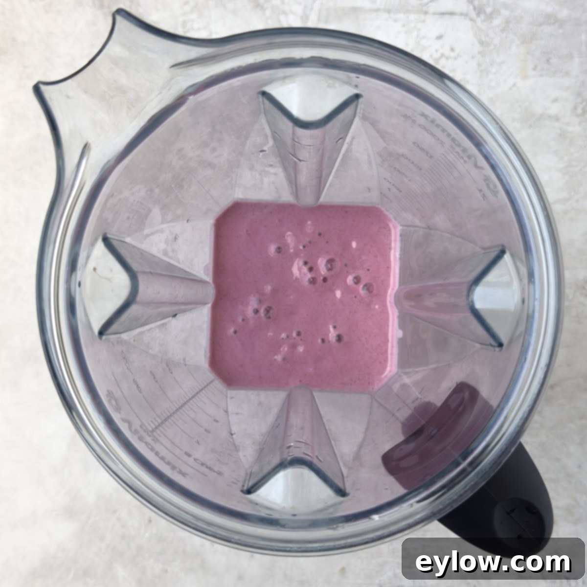 A bright pink raspberry smoothie in the blender. 