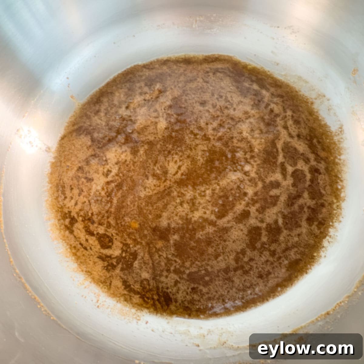 A pot with melting brown sugar, maple syrup, butter and oil for candied pecans, stirred until smooth.