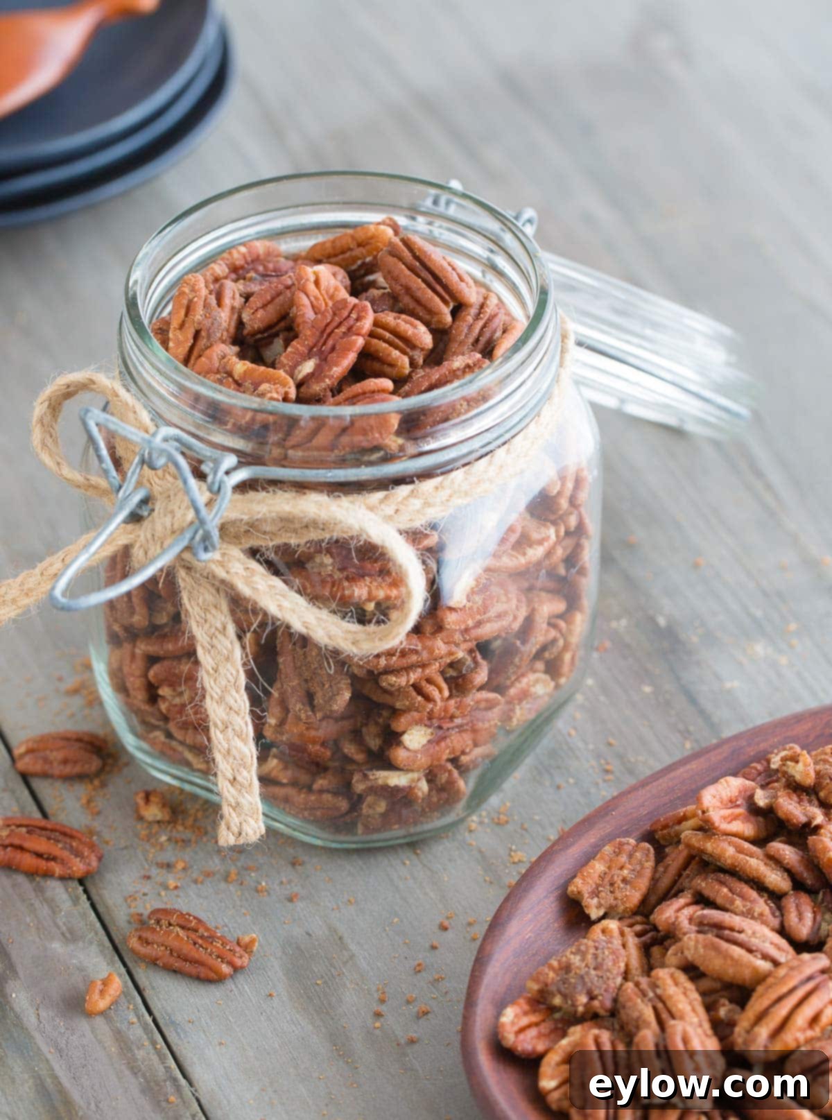 A glass jar of candied pecans tied with a rustic jute ribbon, presented as a lovely gift.
