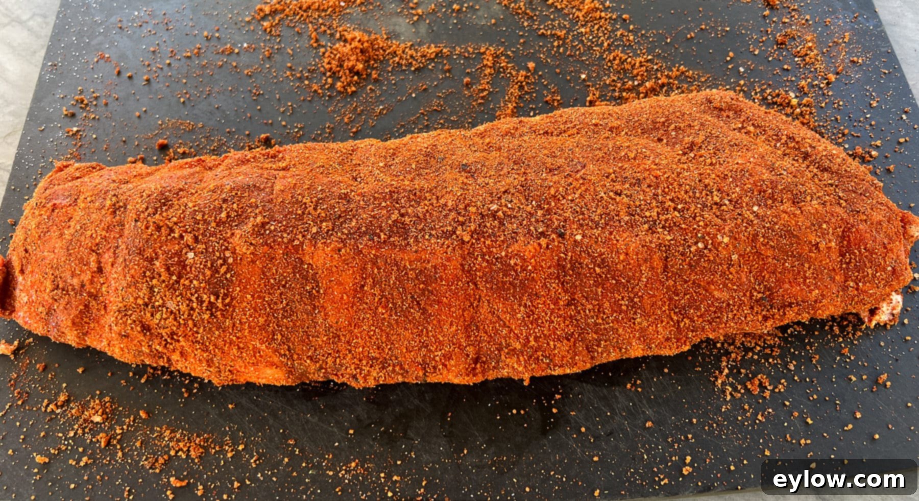 A rack of baby back ribs coated in dry rub, ready for the grill.