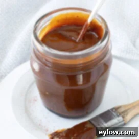 A glass jar of deep red homemade bbq sauce.