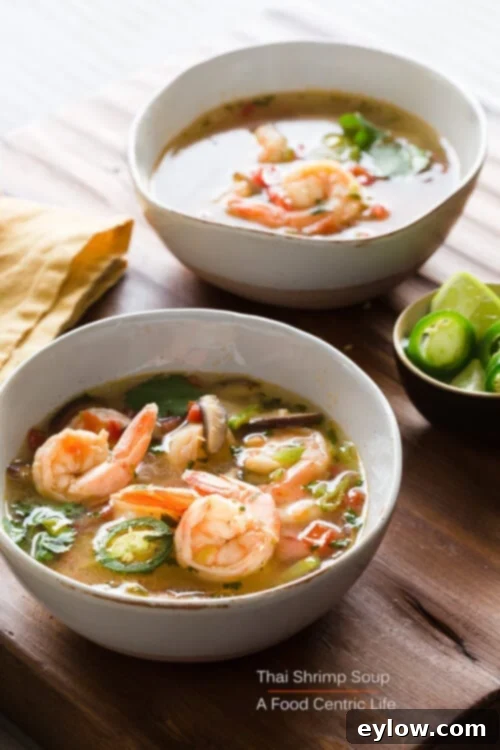 Exquisite Thai shrimp soup (Tom Yum Goong) served in elegant individual bowls, garnished with fresh herbs and chili, highlighting the vibrant colors and inviting aroma.