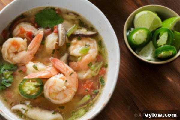 A beautifully presented bowl of Thai Tom Yum soup, showcasing the rich, clear broth, fresh shrimp, and colorful vegetables, garnished with cilantro.