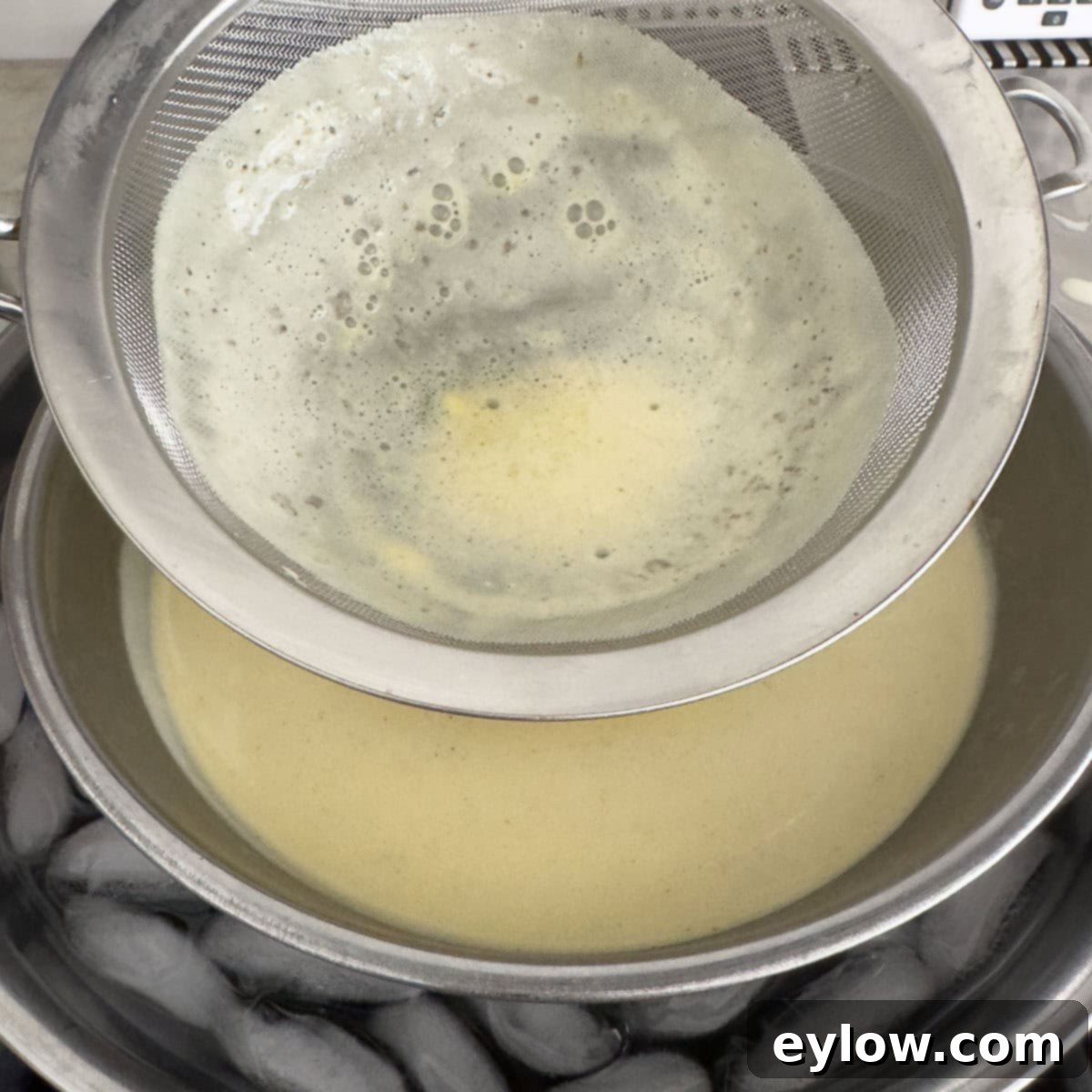 Aromatic Vanilla Bean Bliss 10 Straining custard through a sieve into a bowl in an ice bath.