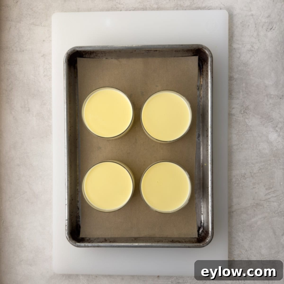 Simply Divine Lemon Posset 7 Four lemon posset desserts in individual glass cups on a tray and white cutting board.