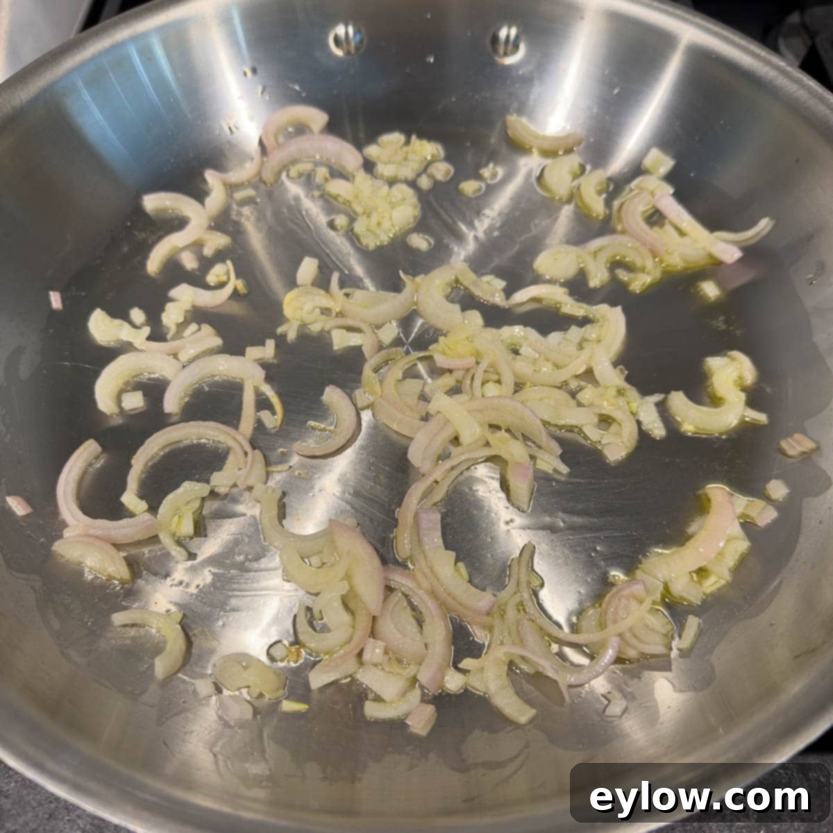Sautéing shallot in olive oil in a fry pan.