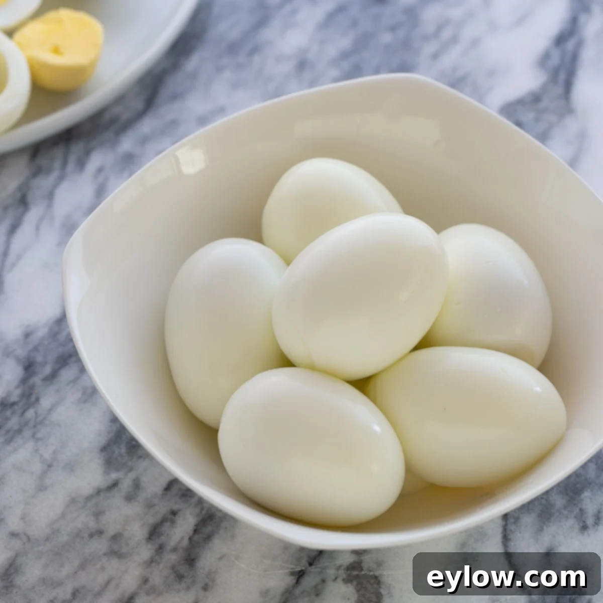 Flawless Hard Boiled Eggs That Peel Effortlessly 2 A small white bowl of perfectly peeled hard-boiled eggs, ready to eat.