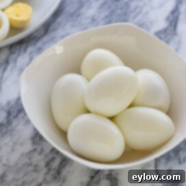 Flawless Hard Boiled Eggs That Peel Effortlessly 7 A small white bowl of peeled hard-boiled eggs.