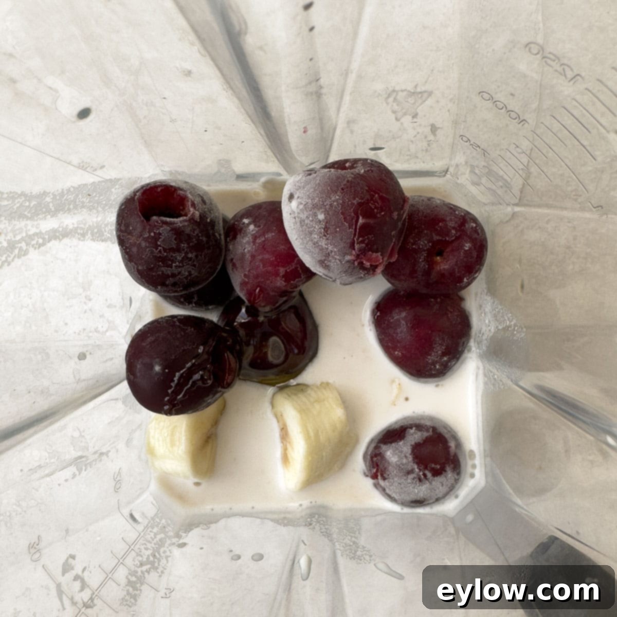 Easy 5-Minute Cherry Smoothie 4 Cherries, banana, and milk being added to a blender container before blending.