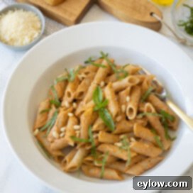 Velvety Sun-Dried Tomato Pesto Pasta 9 A white bowl of sun-dried tomato pesto pasta with basil and parmesan garnish.