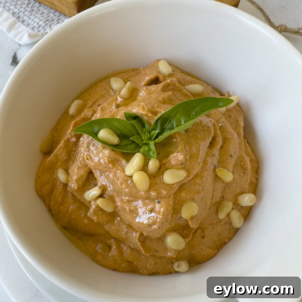 Velvety Sun-Dried Tomato Pesto Pasta 7 Sun-dried tomato whipped ricotta dip in a white bowl garnished with pine nuts and basil.
