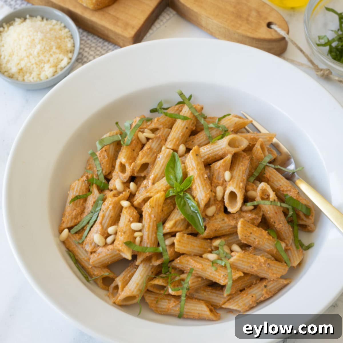 Velvety Sun-Dried Tomato Pesto Pasta 8 A white bowl of sun-dried tomato pesto pasta garnished with fresh basil and parmesan.