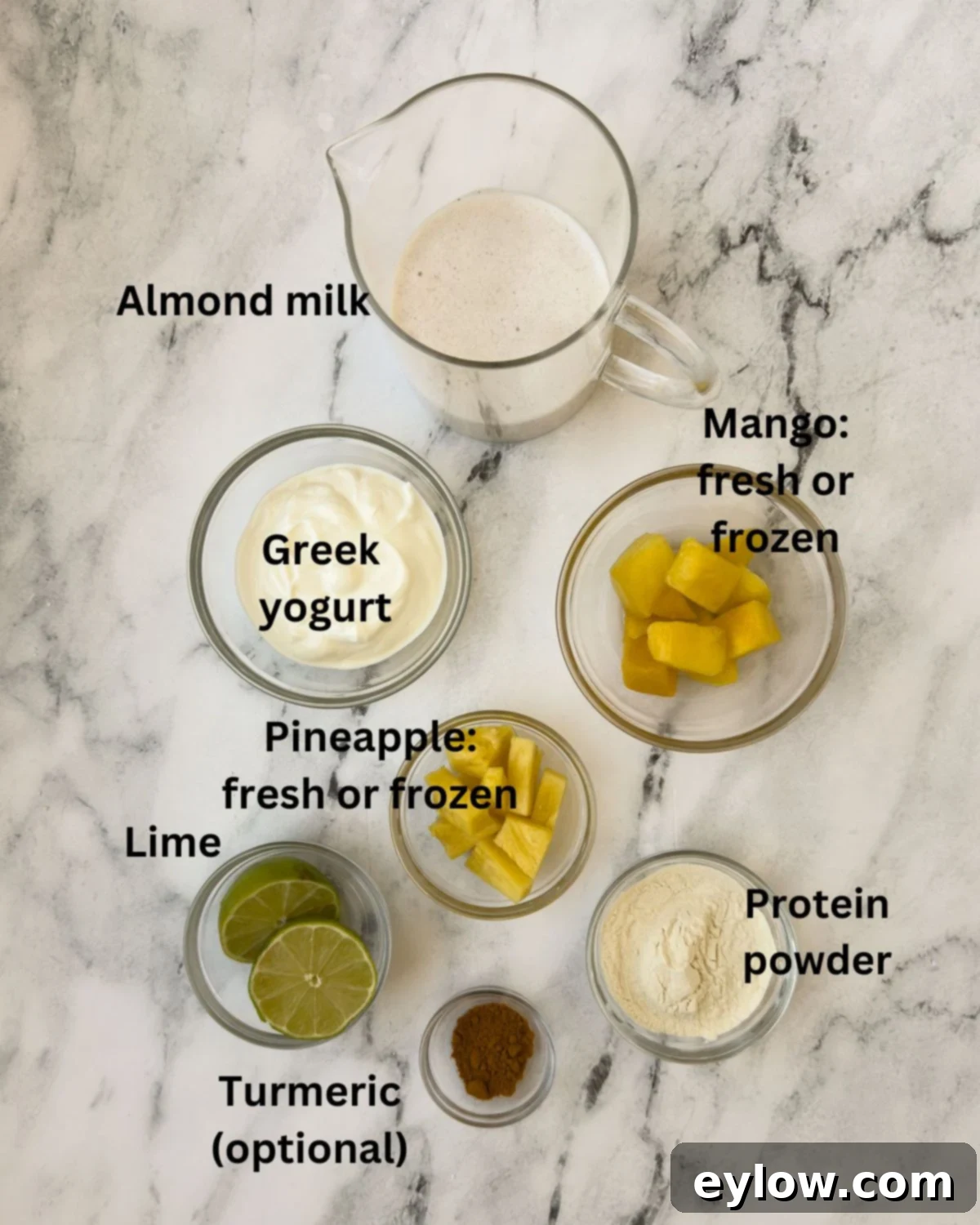 Two glasses of bright golden mango pineapple smoothies with lime and pineapple wedges.