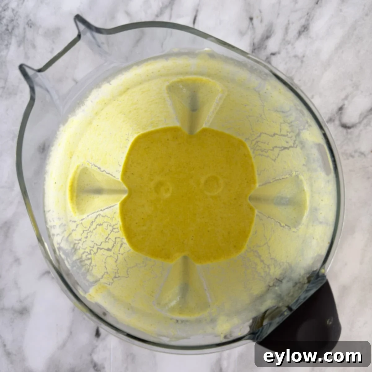 A pureed mango smoothie in a blender ready for pouring.