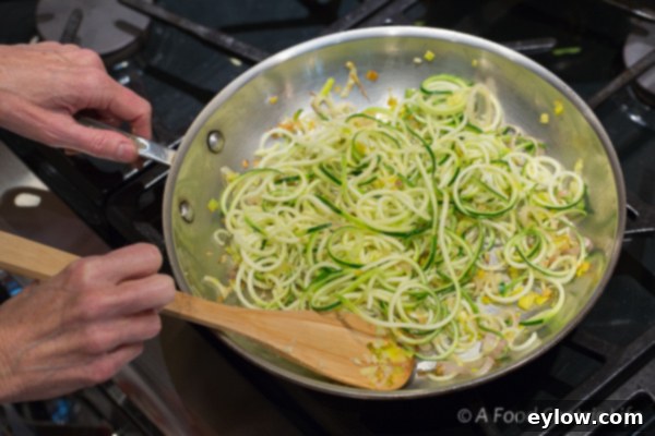 Cooked zucchini noodles with shallots and garlic.